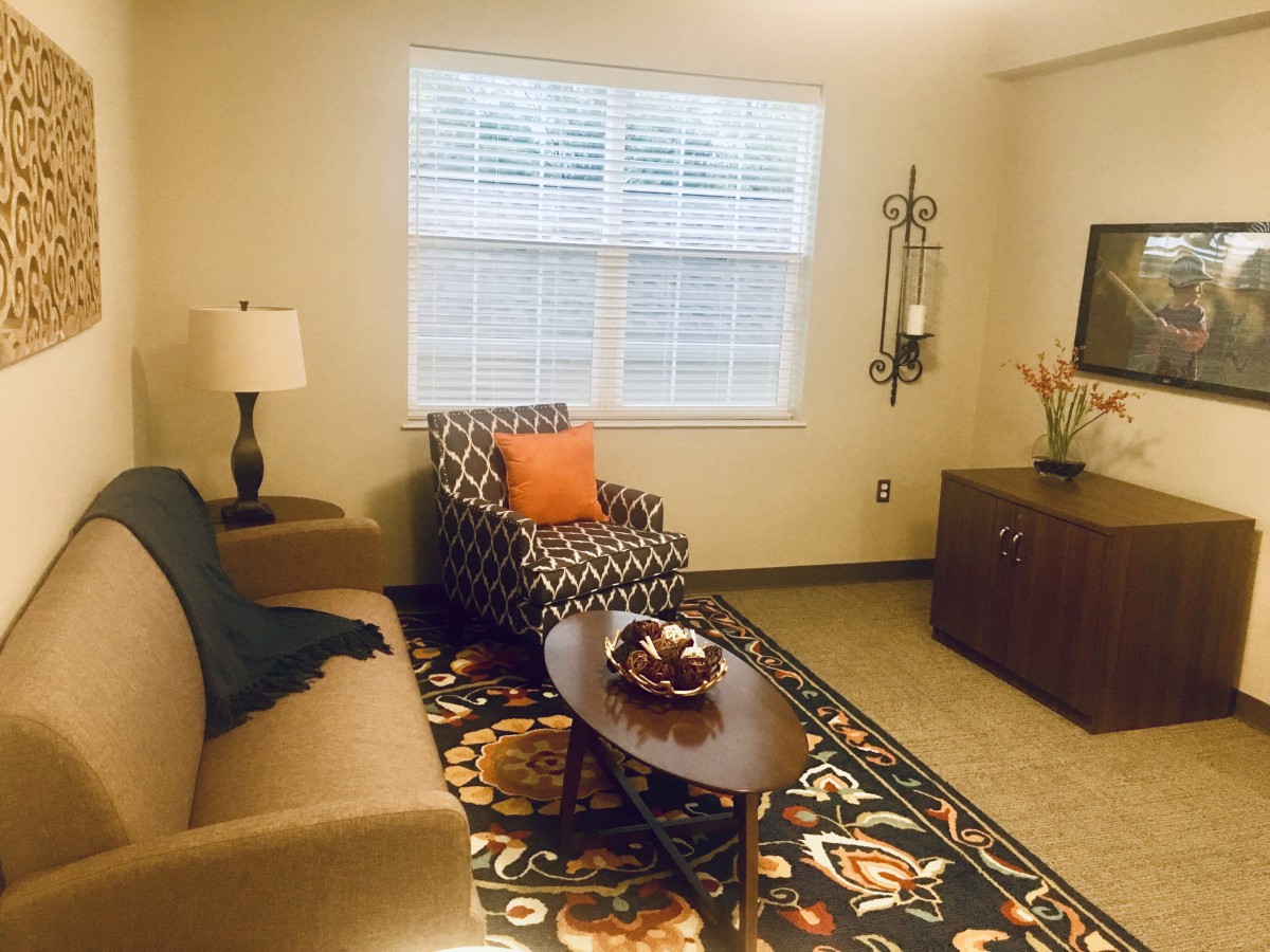A cozy living room with a sofa, patterned armchair, coffee table, and decorative elements.