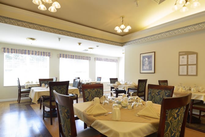 An elegantly set dining area with neatly arranged tables and chairs in a well-lit restaurant interior.