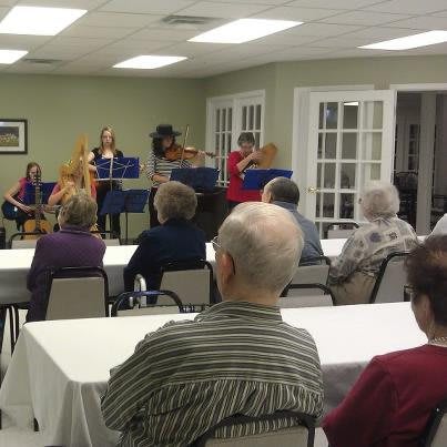 An indoor musical performance with an audience seated at tables.