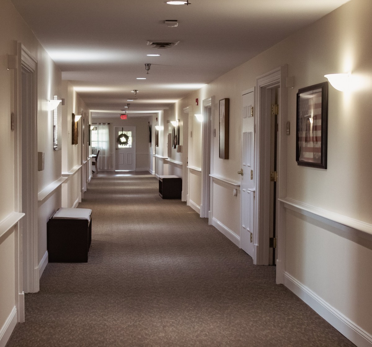 A well-lit, carpeted hallway with doors and artwork on the walls.