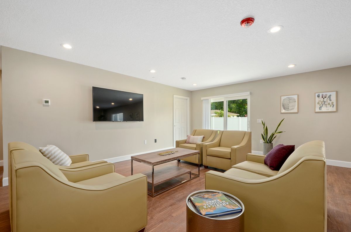 A modern living room with beige sofas, a coffee table, and a wall-mounted TV.
