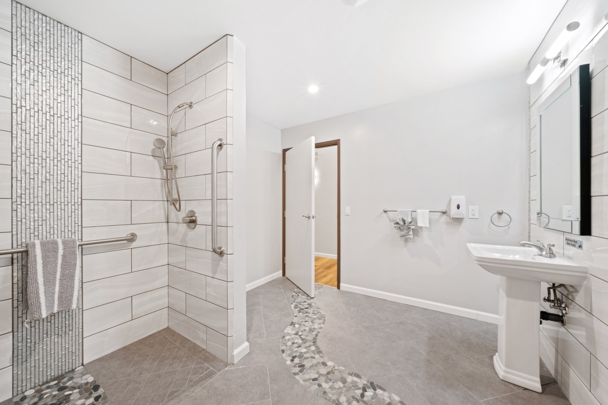 A modern, accessible bathroom with a tiled walk-in shower and grab bars.