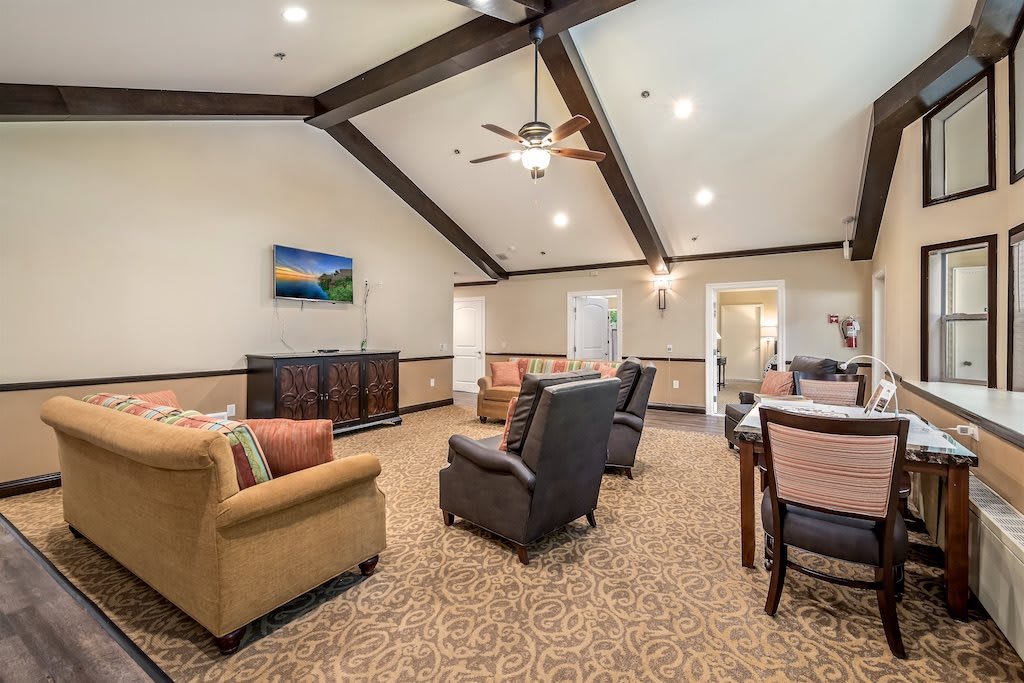 A spacious living room with a cozy seating arrangement, featuring ceiling beams and a television.
