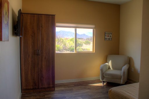A cozy room with a window showcasing mountain views, featuring simple furniture and warm tones.