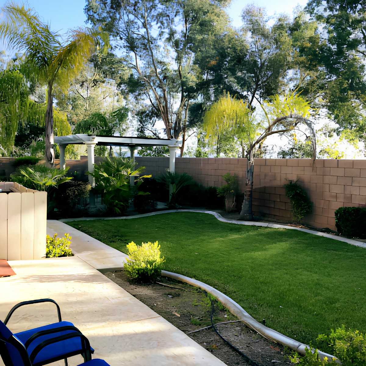 A peaceful backyard with green lawn and trees, featuring a patio area.