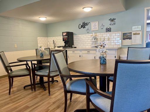 A cozy dining area featuring tables, chairs, and a coffee station in a modern kitchenette.