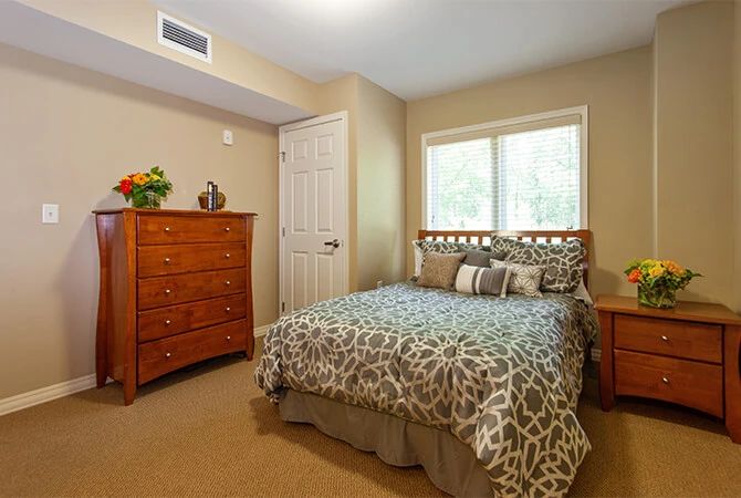A cozy bedroom with a wooden dresser and a patterned bedspread.