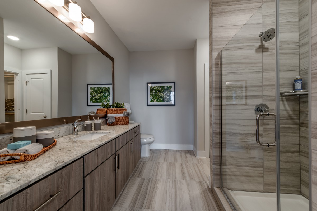 A modern bathroom featuring a double sink vanity, large mirror, and a glass-enclosed shower.