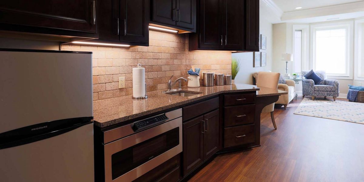 A modern kitchen with dark wood cabinets, a sleek countertop, and stainless steel appliances.
