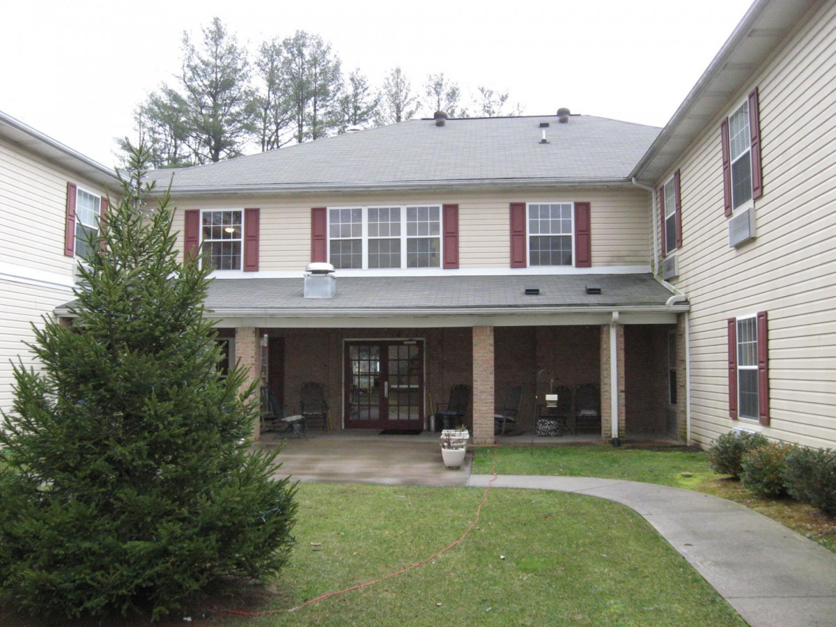 A two-story residential building with a lawn and trees in front.