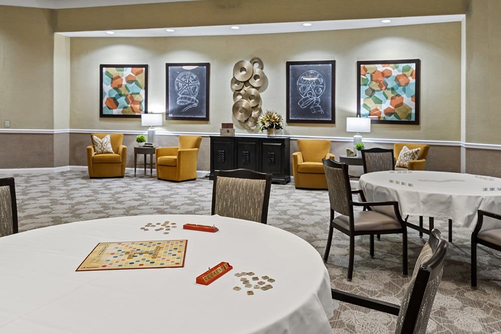 A modern game room with tables set for board games, comfortable seating, and decorative artwork on the walls.