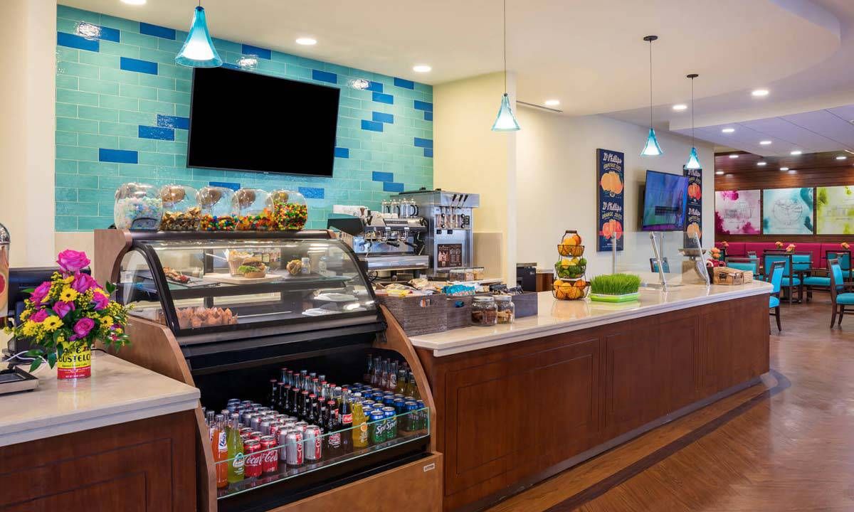 A modern cafe interior with a well-stocked display case and beverage cooler.