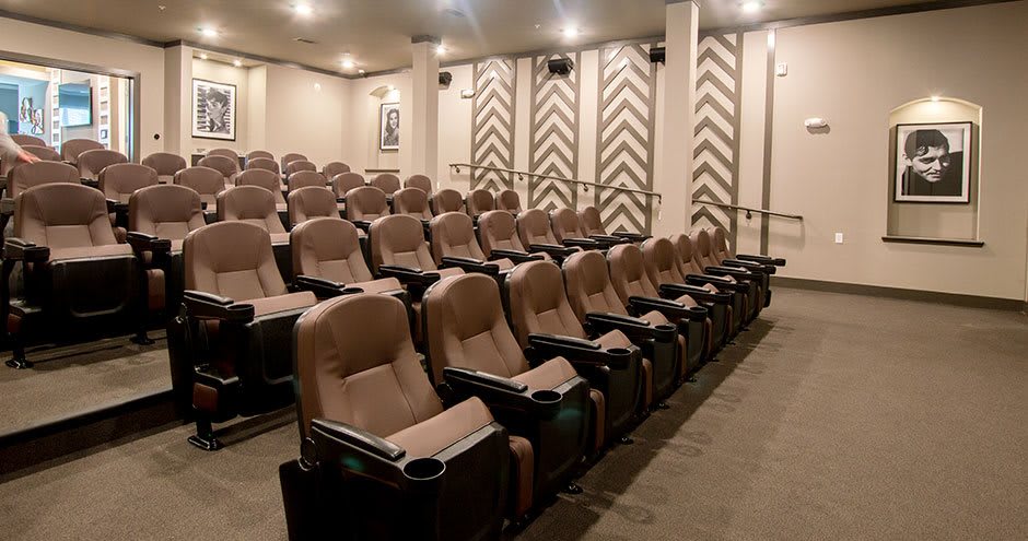 An empty, modern theater with comfortable seating arranged in rows.