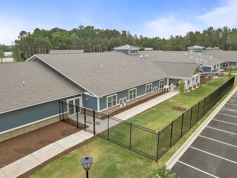 Aerial view of a large building surrounded by greenery and a fenced area.