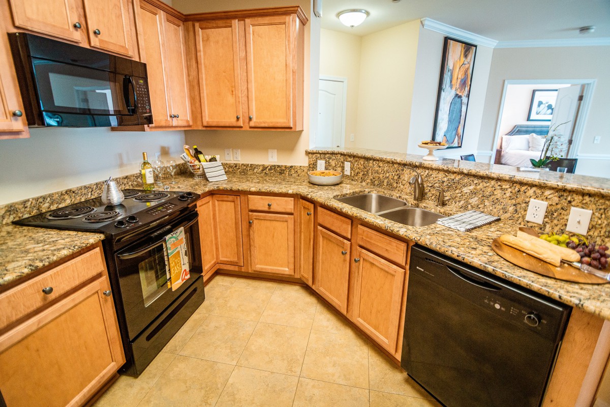 A modern kitchen with wooden cabinets and granite countertops, equipped with an oven, microwave, and dishwasher.