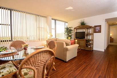 Cozy living room with natural light, featuring a sofa, television, and dining area.