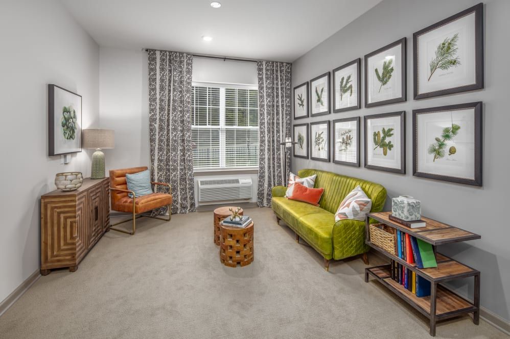 A modern living room with a green sofa, wall art, and a cozy reading corner.