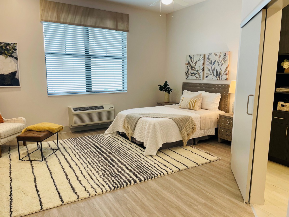A modern and minimalist bedroom with a cozy bed, decorative rug, and large window.
