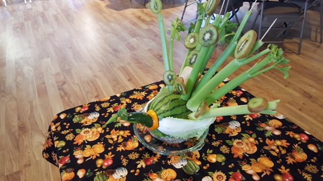 A creative food art display featuring a peacock made from carved fruits and vegetables.