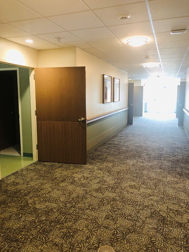 A view of a well-lit hallway featuring doors on either side and carpet flooring.