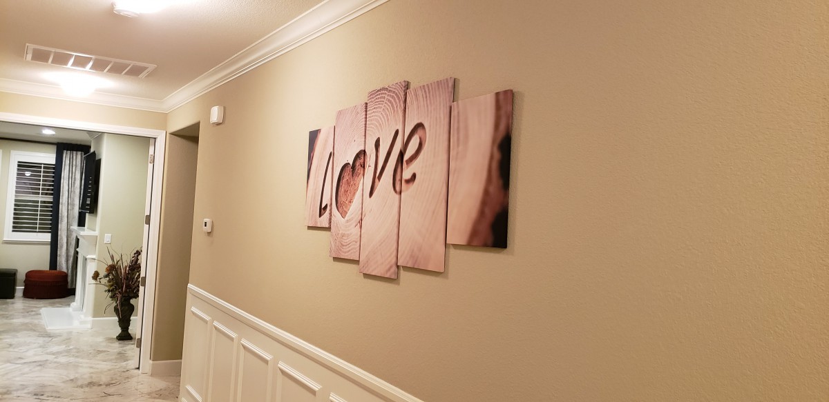A multi-panel wall art piece with the word 'Love' displayed in a hallway.