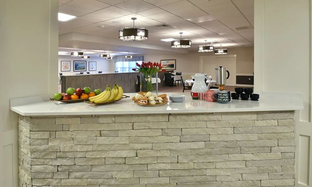 A modern office reception area with a refreshment setup including fruits, croissants, and coffee.
