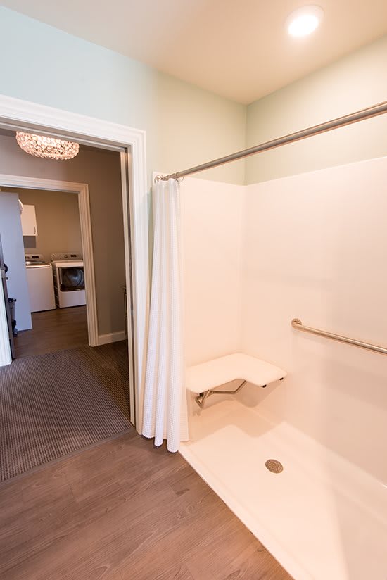 An accessible bathroom featuring a shower with a grab bar and foldable seat.