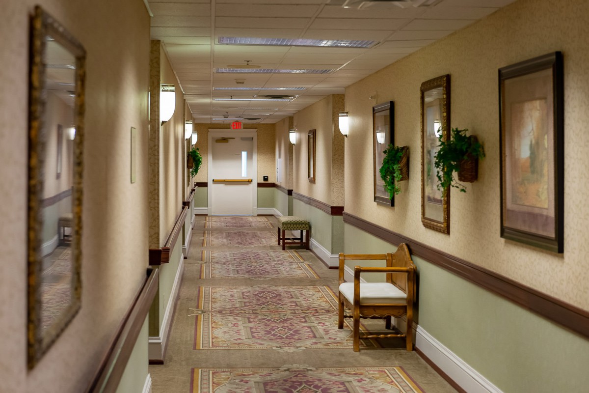 A long, carpeted hallway with chairs and wall decorations.