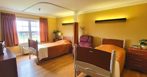 A well-lit hospital room featuring two beds and a comfortable seating area.