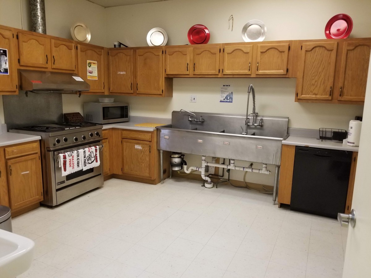 A spacious kitchen with wooden cabinets and industrial sink.