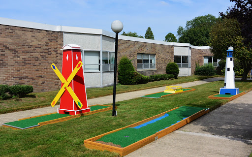 A vibrant mini golf course featuring a decorative windmill and neatly maintained greens.