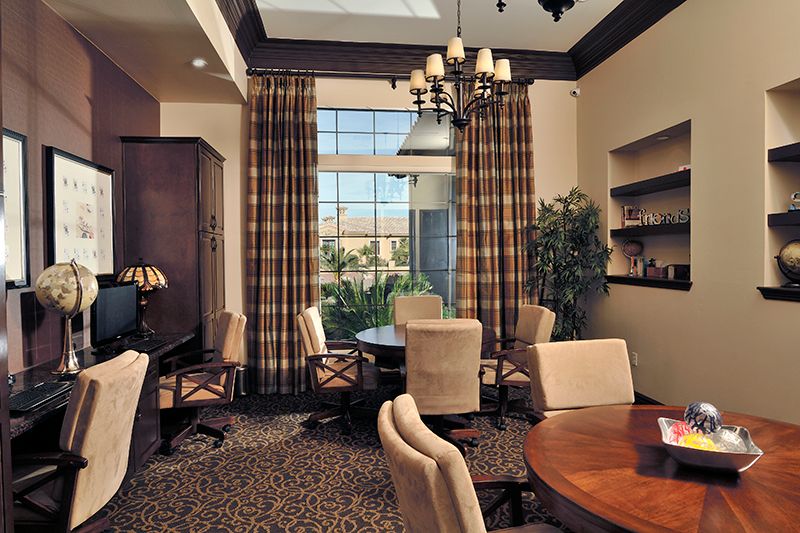 A modern office space with comfortable chairs, a large wooden table, and natural lighting from tall windows.