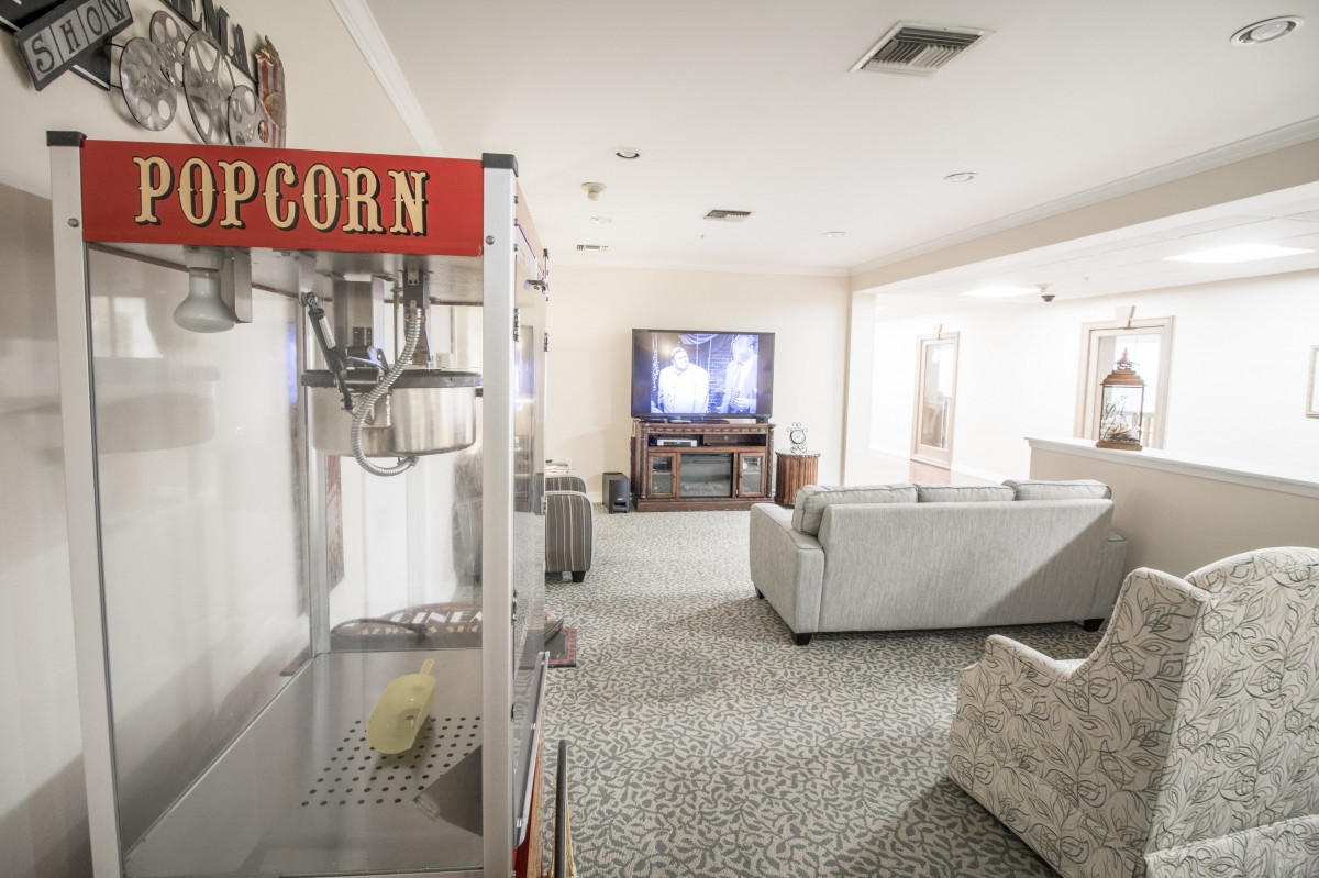 A cozy home theater setup with a popcorn machine and comfortable seating facing a large television.
