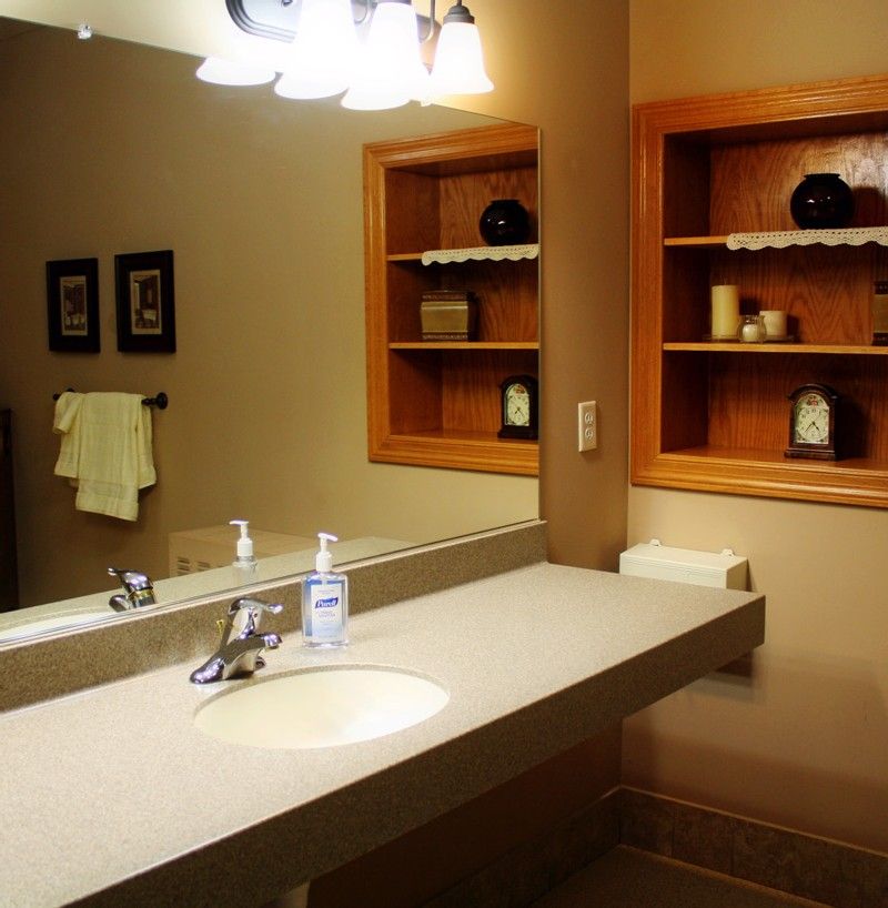 A well-lit bathroom with a mirror, sink, and organized shelves.