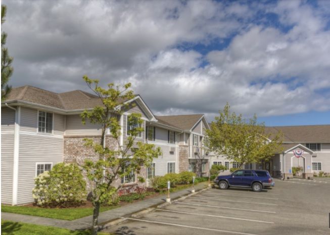 A suburban building with a parking lot and cloudy sky.
