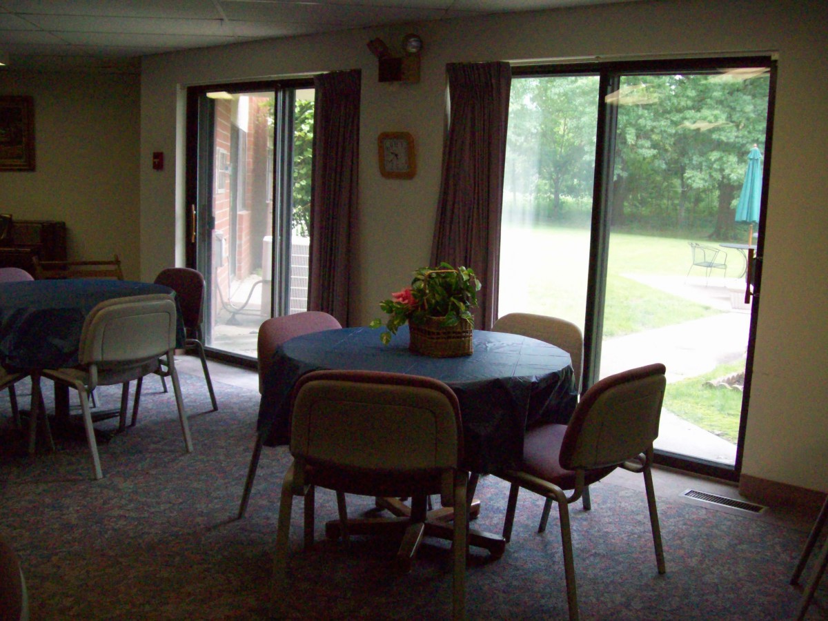 A cozy dining area with round tables and chairs, illuminated by natural light from large windows.