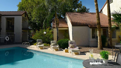 A serene outdoor setting featuring a glistening pool surrounded by comfortable sun loungers and picturesque landscaping.