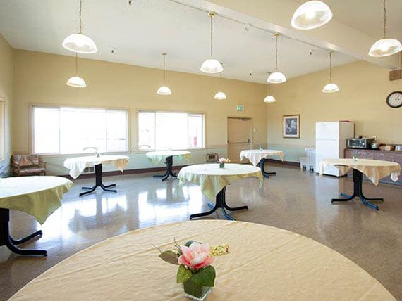 A bright dining room with tables decorated with rose centerpieces and plenty of natural light.