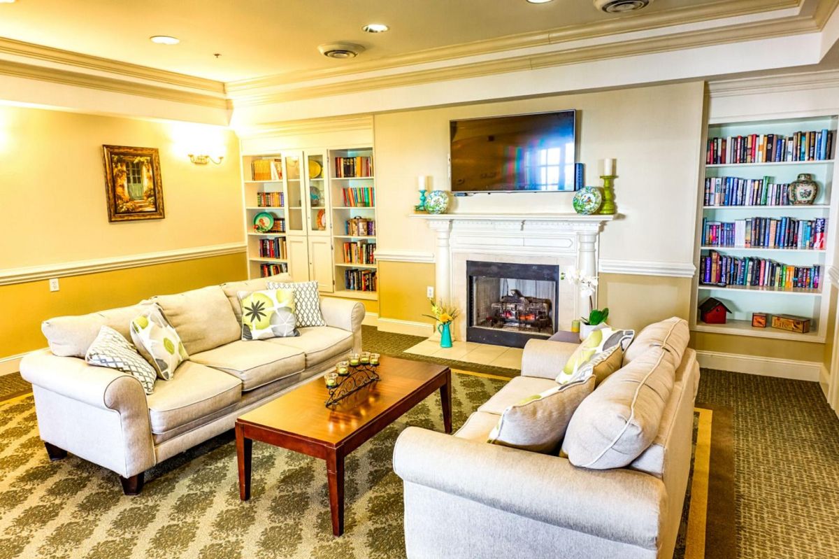 A cozy living room featuring comfortable sofas, a fireplace, and a bookshelf.