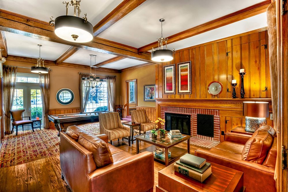 A cozy living room with wood paneling, leather furniture, a fireplace, and a pool table.