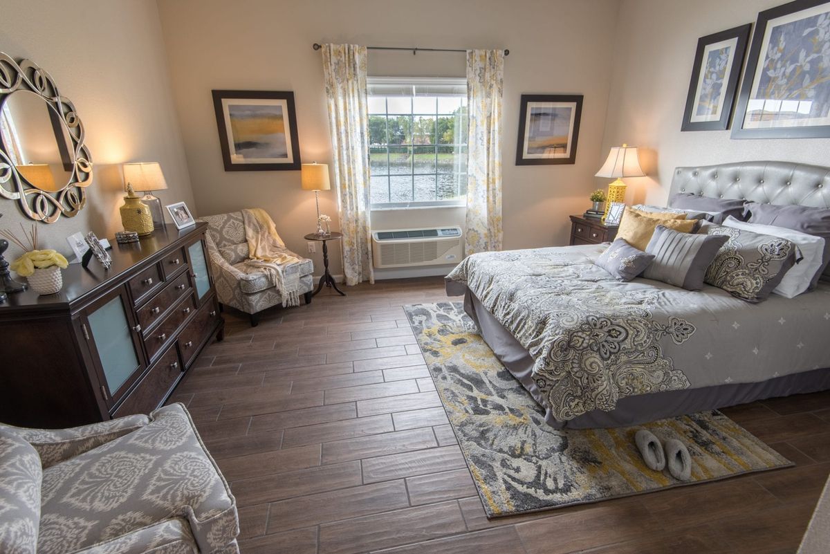 A cozy bedroom with elegant decor, featuring a large bed, patterned carpet, and soft lighting.