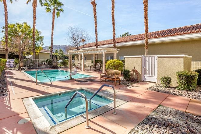 A serene outdoor swimming pool area surrounded by palm trees, perfect for relaxation on a sunny day.