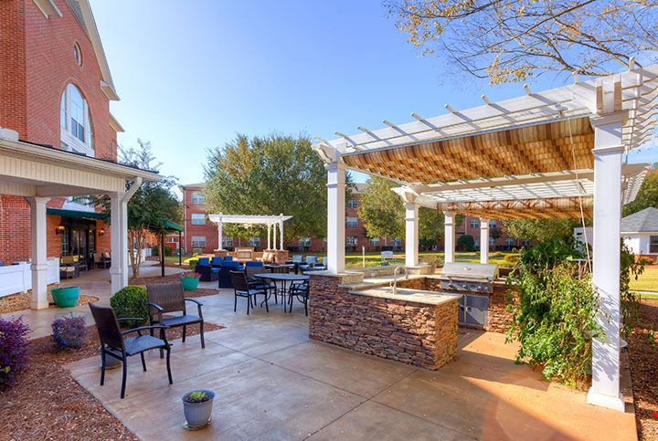 A spacious outdoor patio with seating and pergolas, surrounded by greenery.