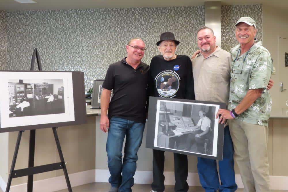 A group of four people posing with black and white photographs at an event.