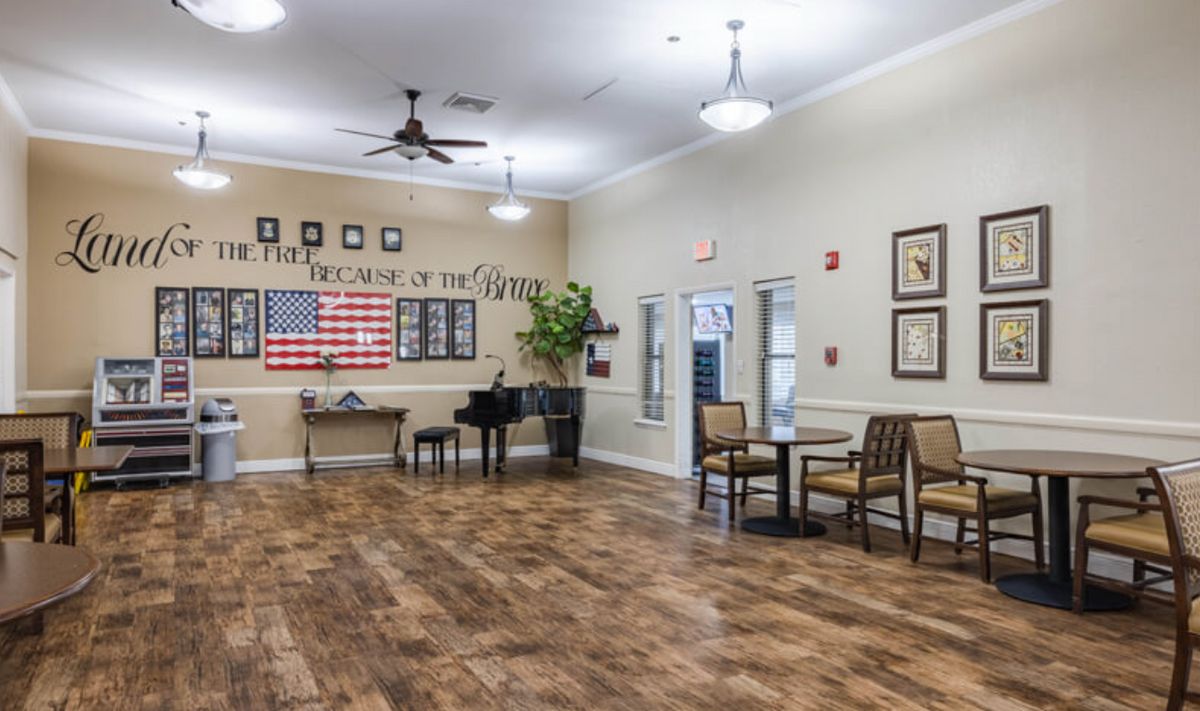 A spacious community room with a piano, American flag decor, and comfortable seating arrangements.