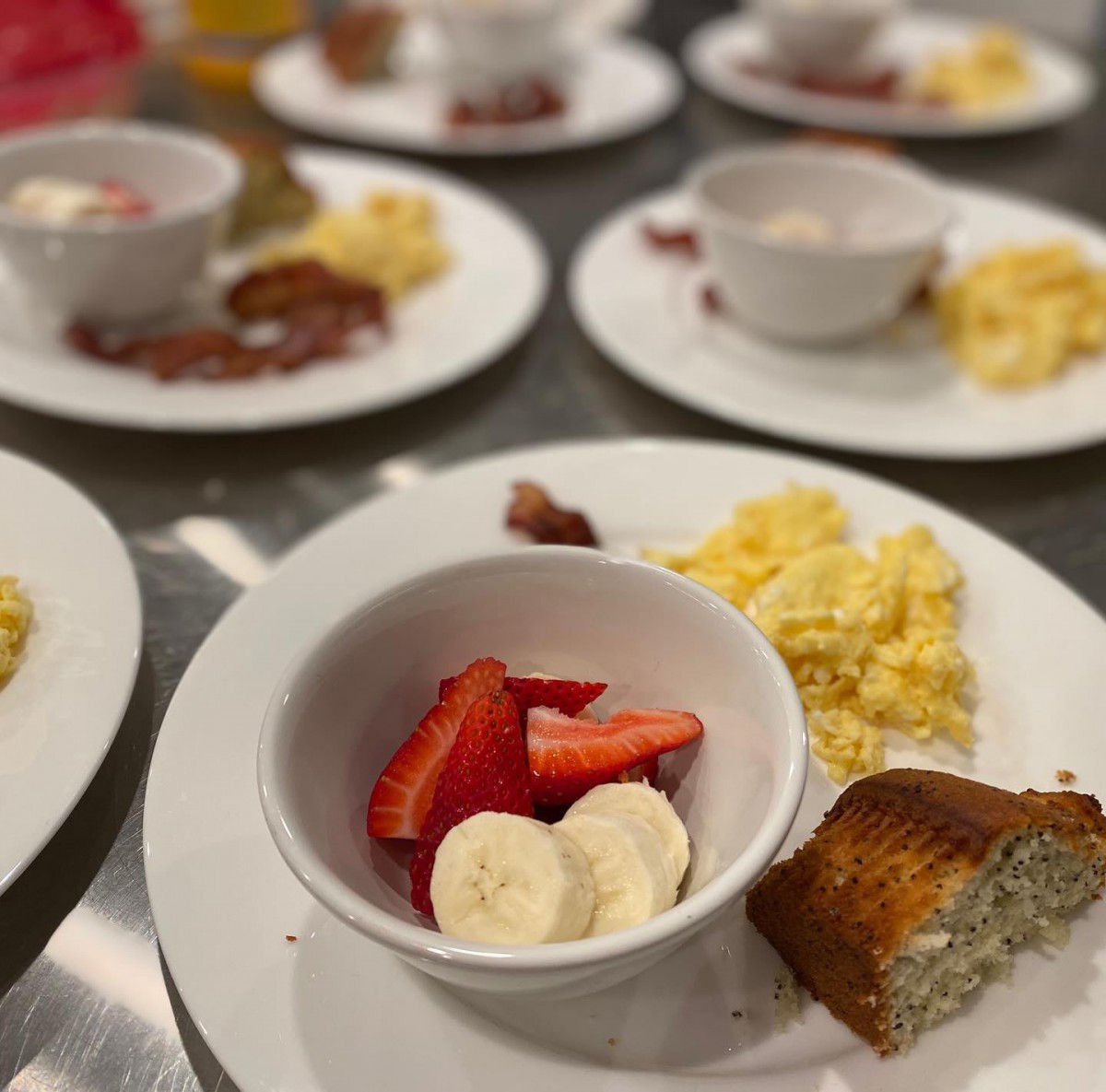 A breakfast spread featuring scrambled eggs, sliced strawberries, banana, and a slice of bread.