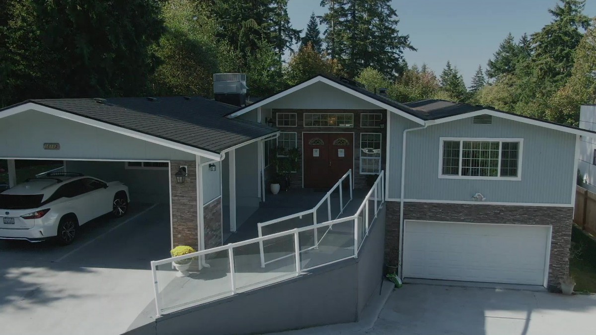 A modern residential house with a garage, surrounded by trees.