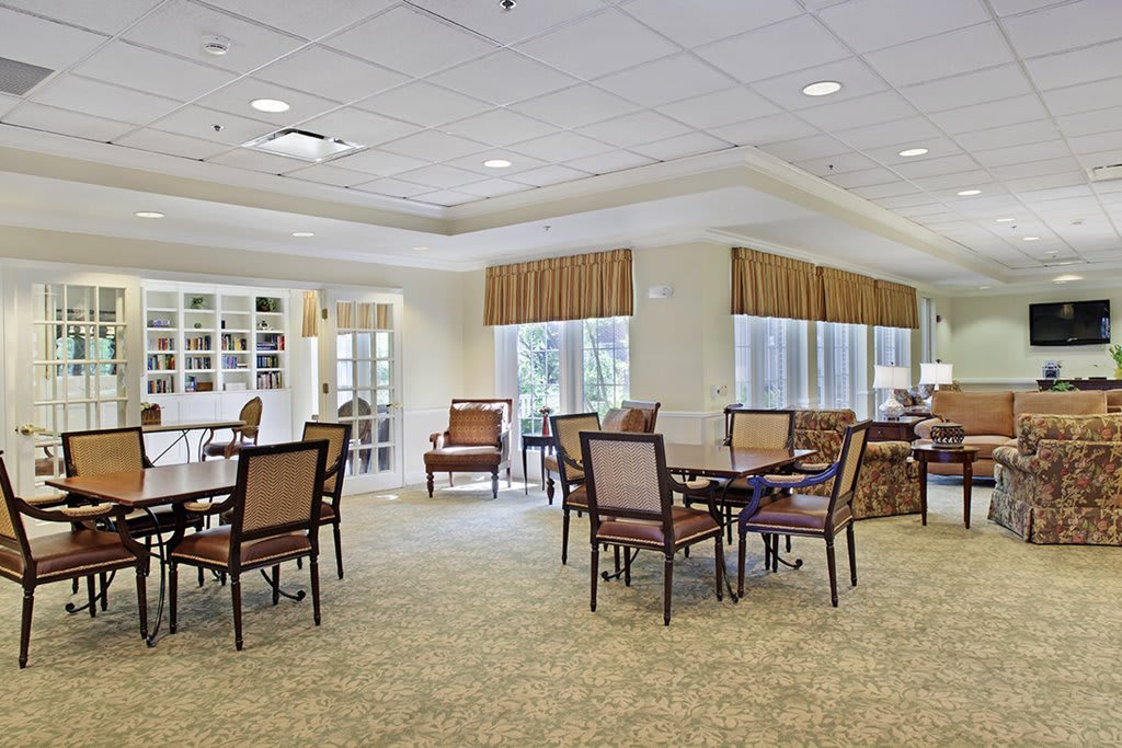 A spacious dining area with several tables and chairs, well-lit with natural light streaming through the large windows.