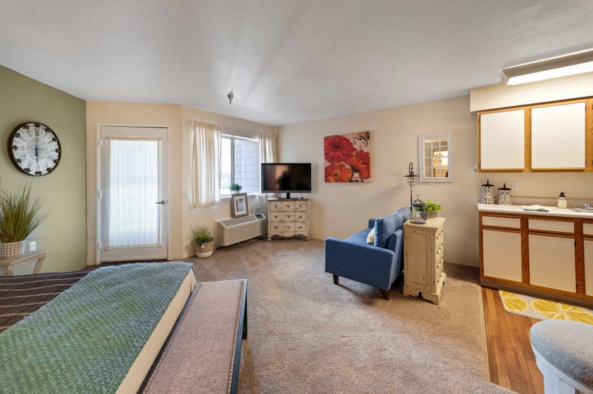 A cozy studio apartment featuring a bed, TV, and seating area with modern decor.