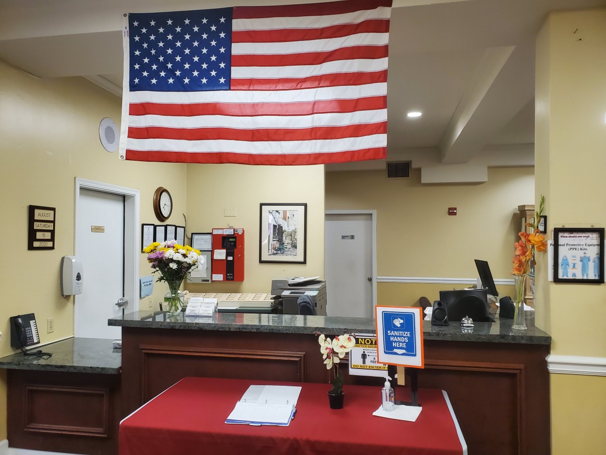 A reception area featuring an American flag, a desk with flowers, and informational signage.